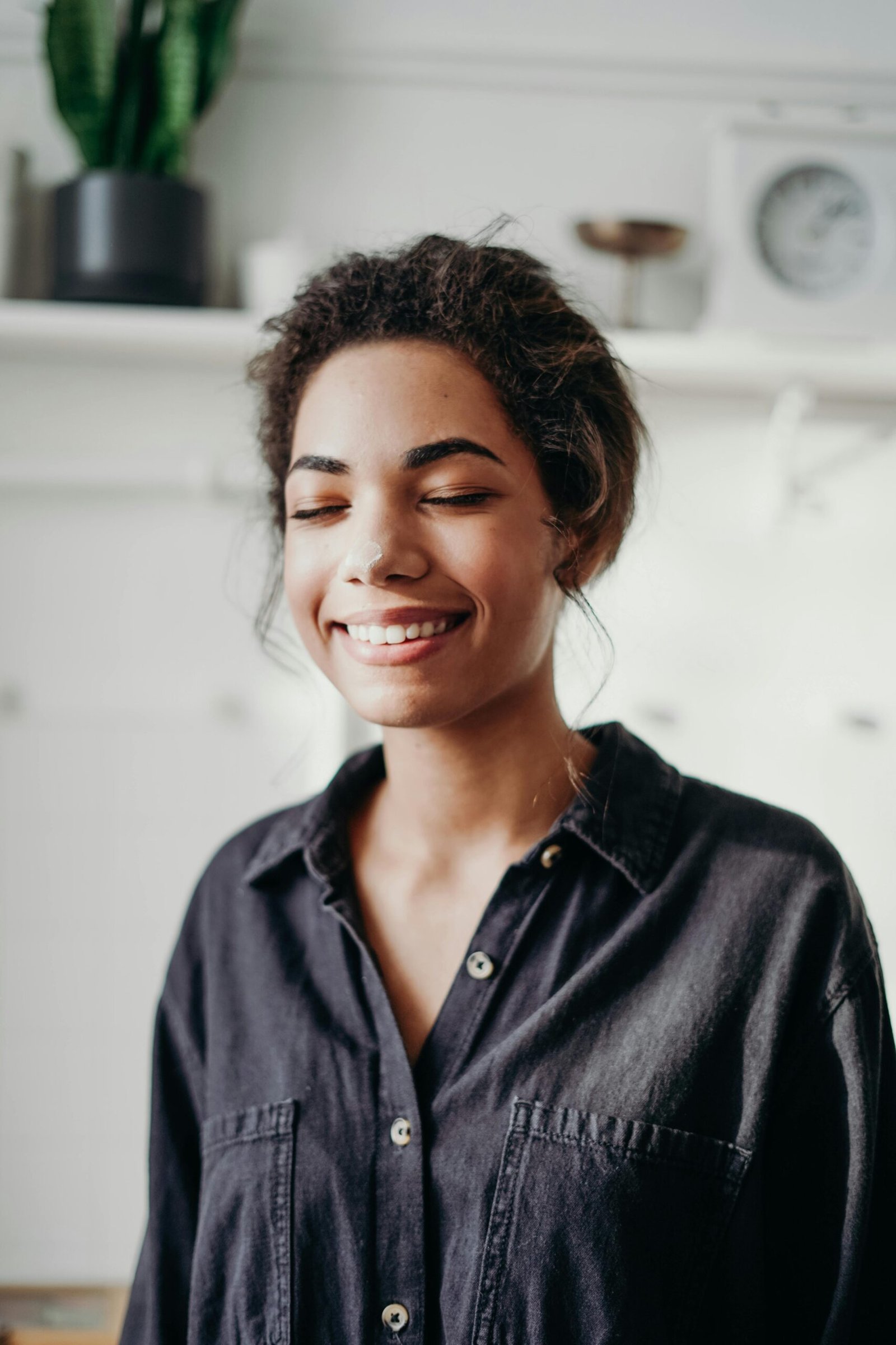 Portrait of a smiling woman indoors with closed eyes in a relaxed pose.